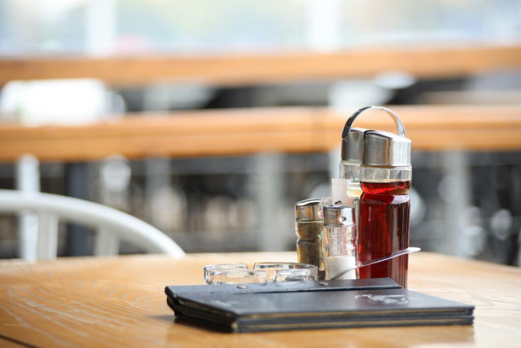 Close-up of a restaurant table with condiments and a menu, ideal for dining themes.