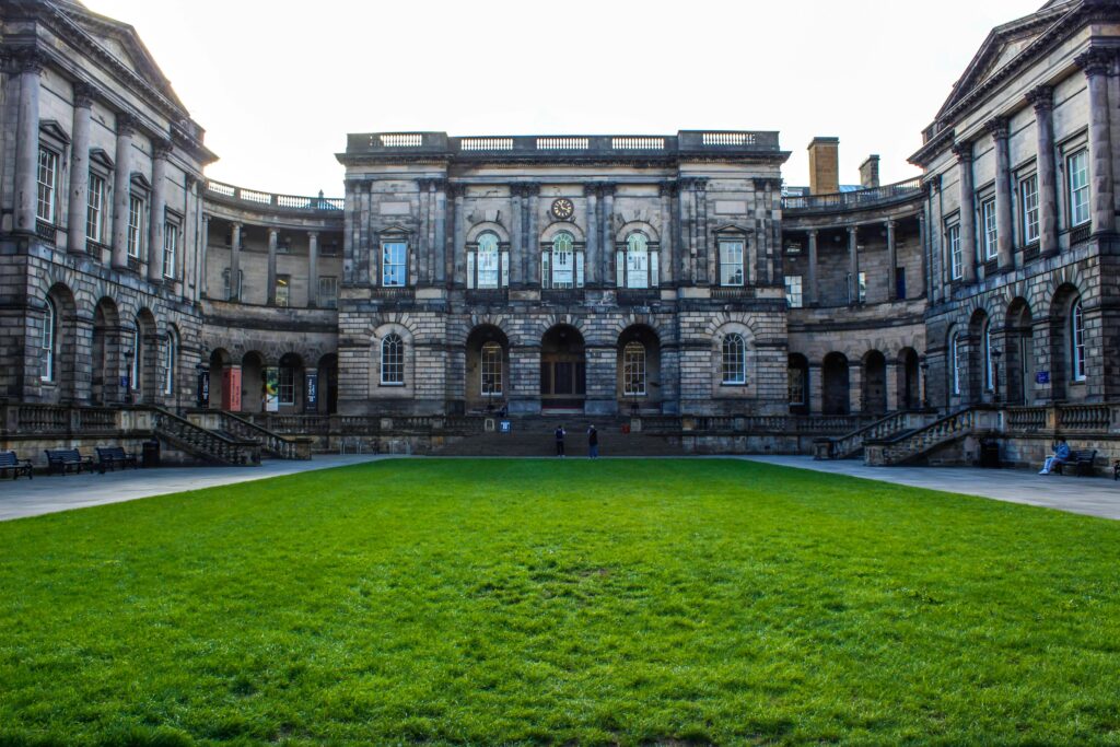 Historic facade of the Edinburgh Law School with a lush green courtyard. Iconic architecture in Scotland.